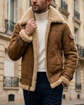 Brown lambswool shearling aviator jacket for men with plush interior, tailored collar, zip front, and layering fit, worn by a male model