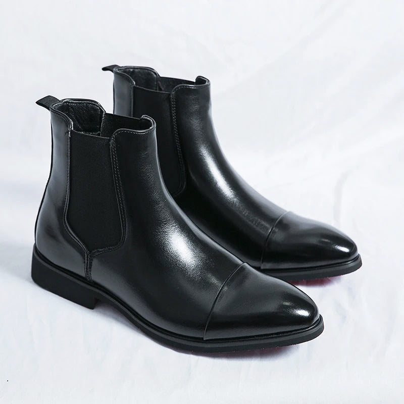 Pair of black leather Chelsea boots with elastic side panels, pull tabs, pointed toes, and low block heels.