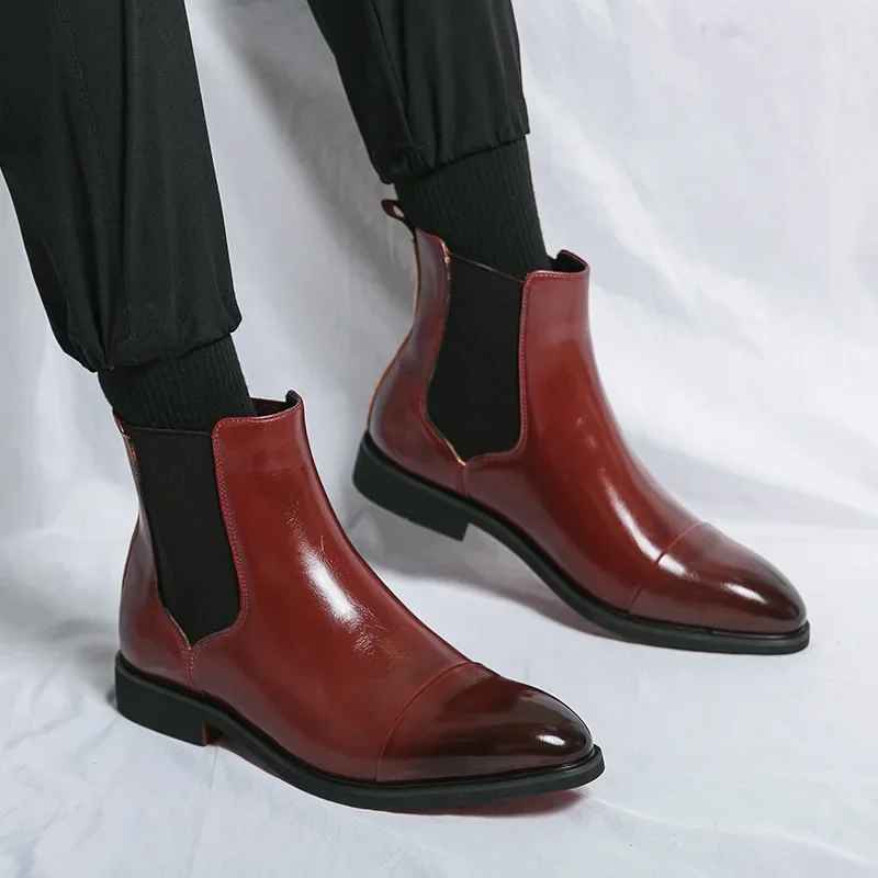 Close-up of burgundy leather cap-toe Chelsea boots worn with black trousers, showing polished cap-toe seam