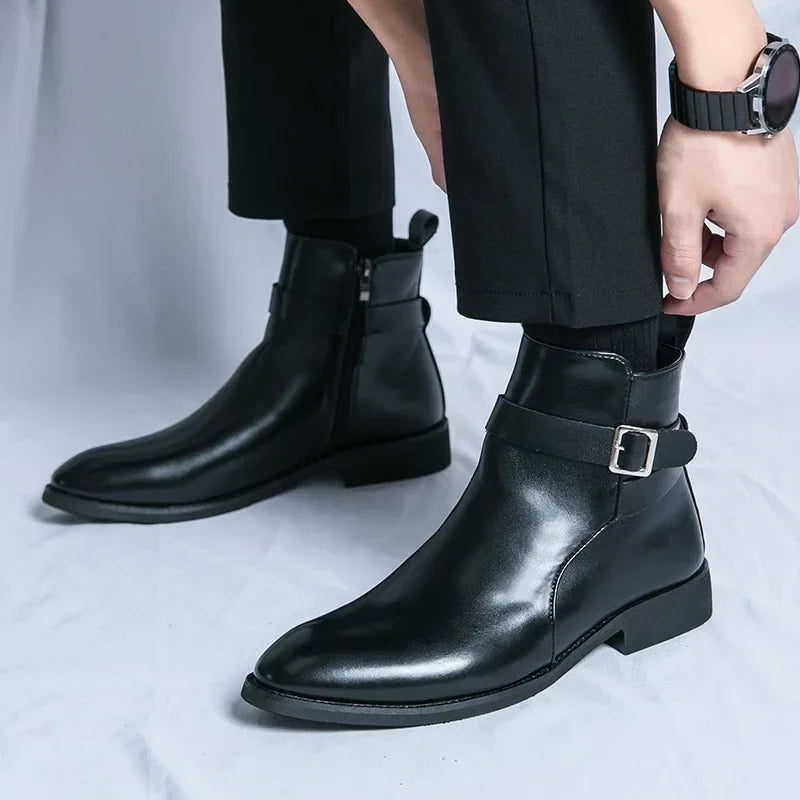 Close-up of black leather ankle boots worn with dark trousers, highlighting the buckled straps and block heels.