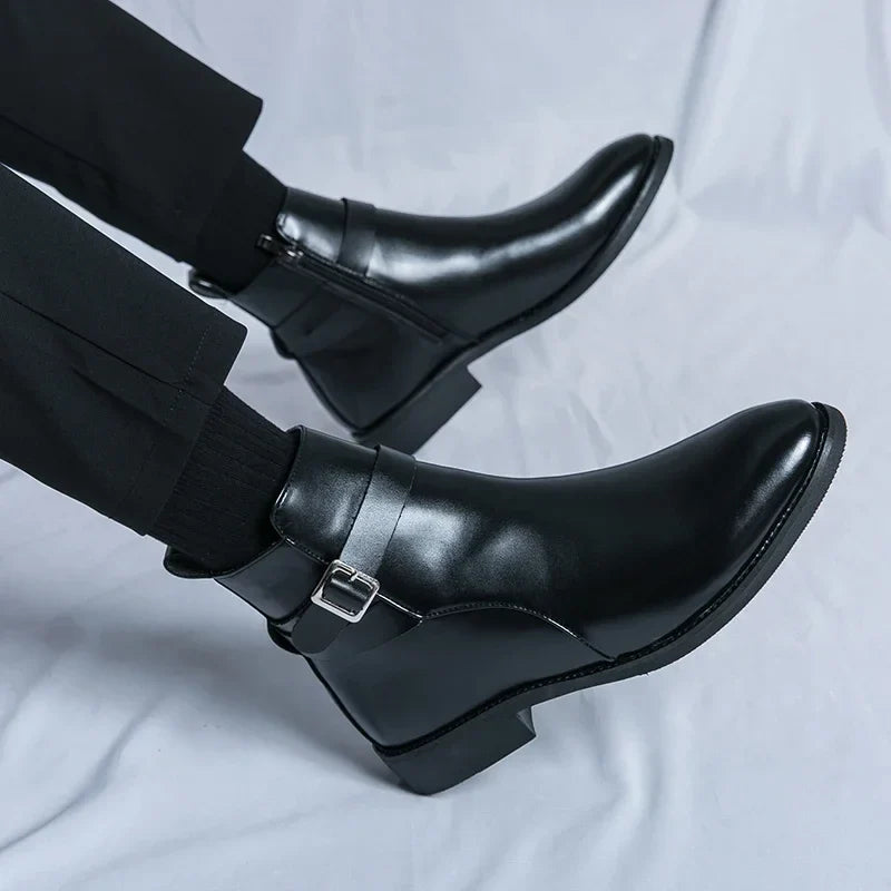 Close-up of black leather ankle boots worn with dark trousers, highlighting the pointed toes and polished finish.
