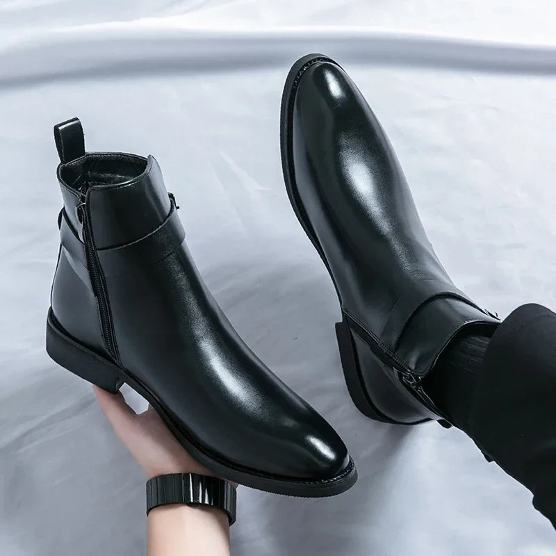 Close-up of a person holding black leather ankle boots, showing the smooth finish and pointed silhouette.