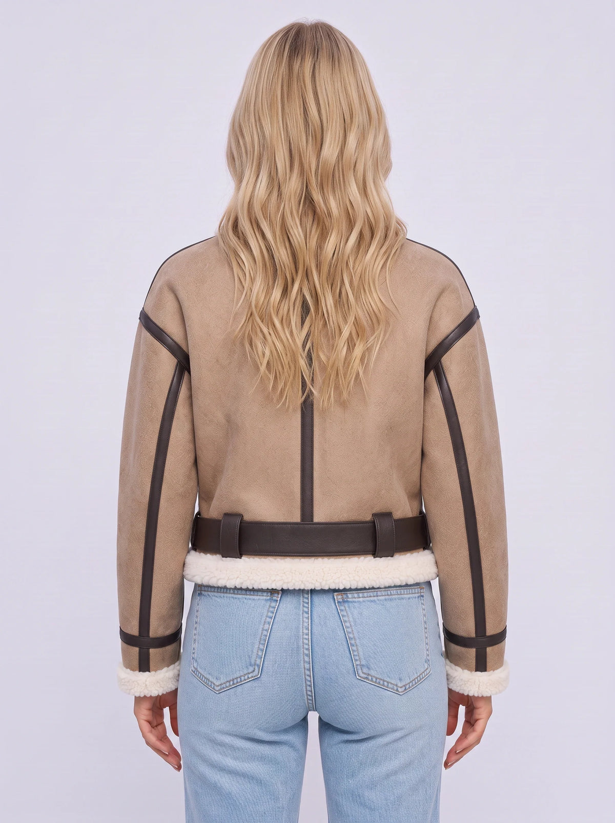 A woman wearing a beige leather shearling aviator jacket with a cropped fit and belted waist, shown from the back