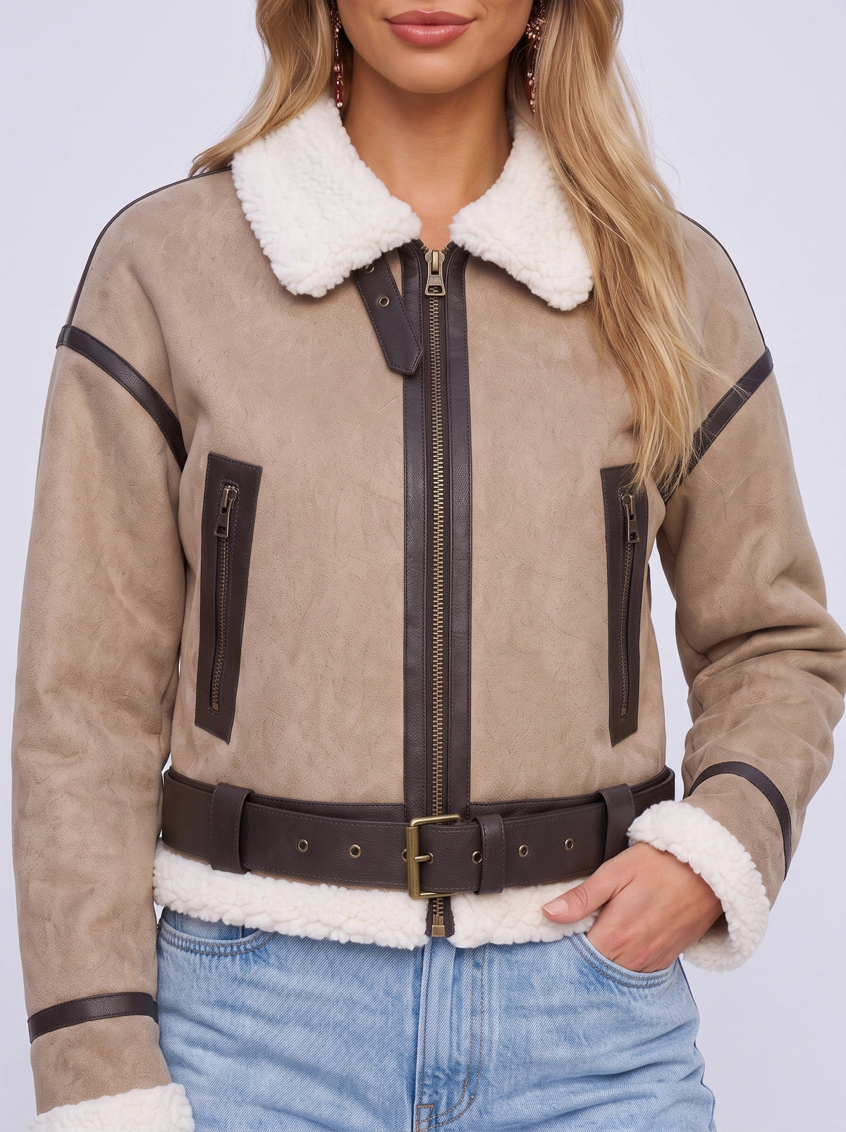 Close-up of a woman wearing a beige leather shearling aviator jacket, showing the shearling collar, zip front, and belted waist