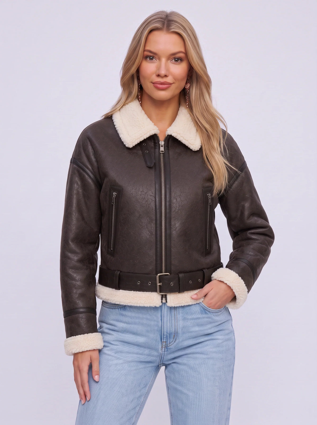 A woman wearing a dark brown leather shearling aviator jacket with a cropped fit, shearling collar, and belted waist
