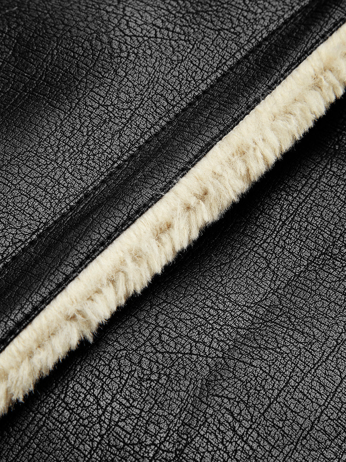 Close-up of a black leather shearling aviator jacket showing the textured leather and shearling trim