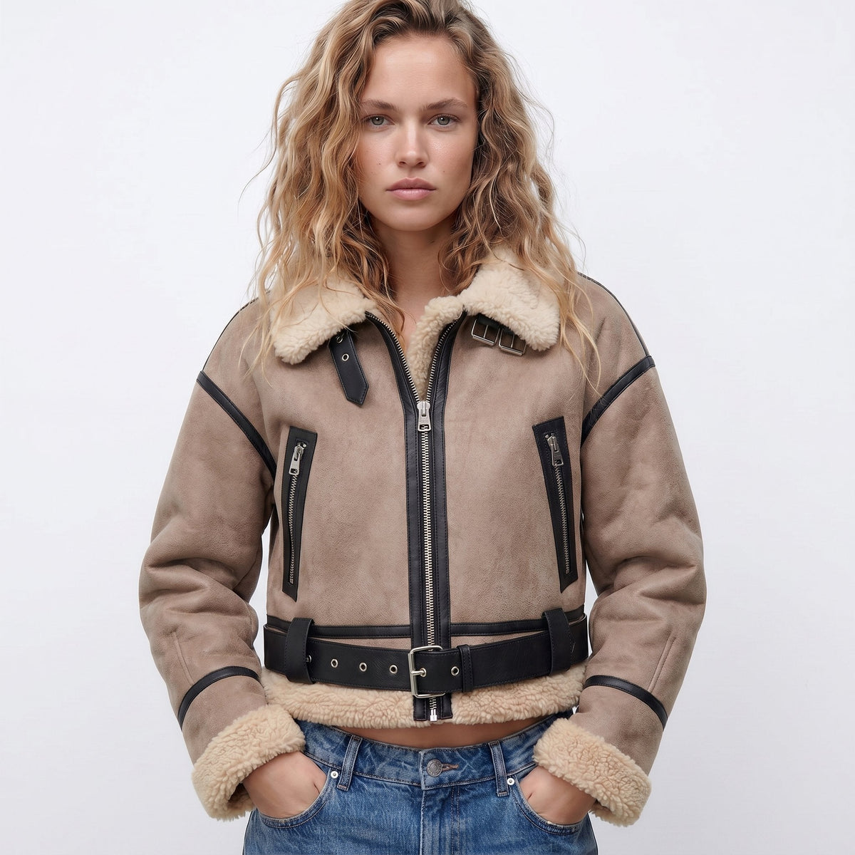 Beige leather shearling bomber jacket worn by a female model, featuring cropped fit, shearling trim, and zip pockets