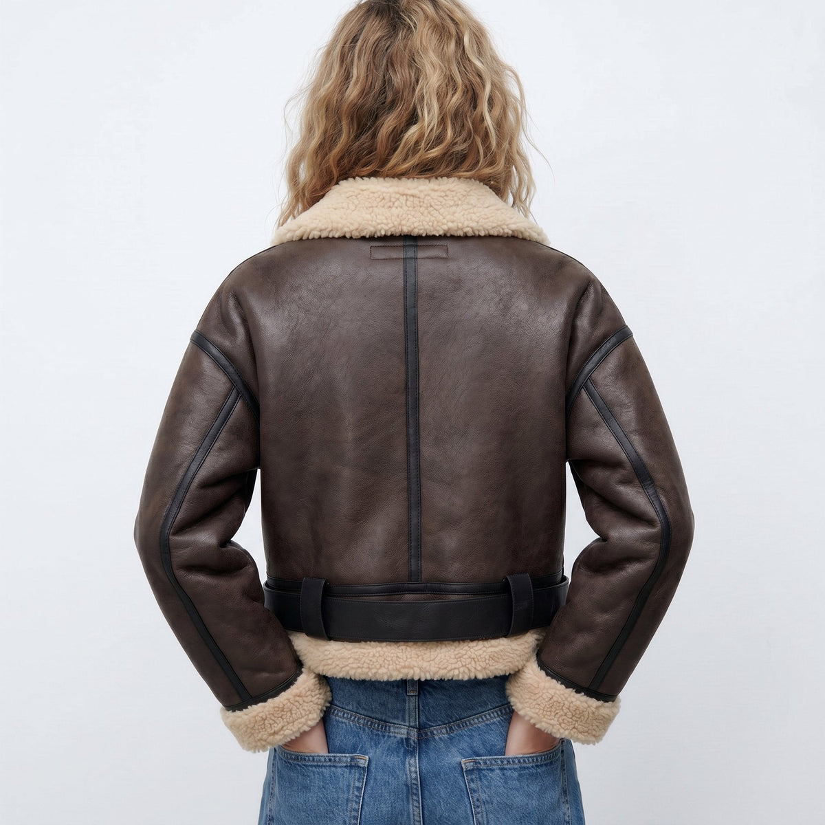 Dark Brown leather shearling bomber jacket worn by a female model, back view with cropped fit and shearling trim