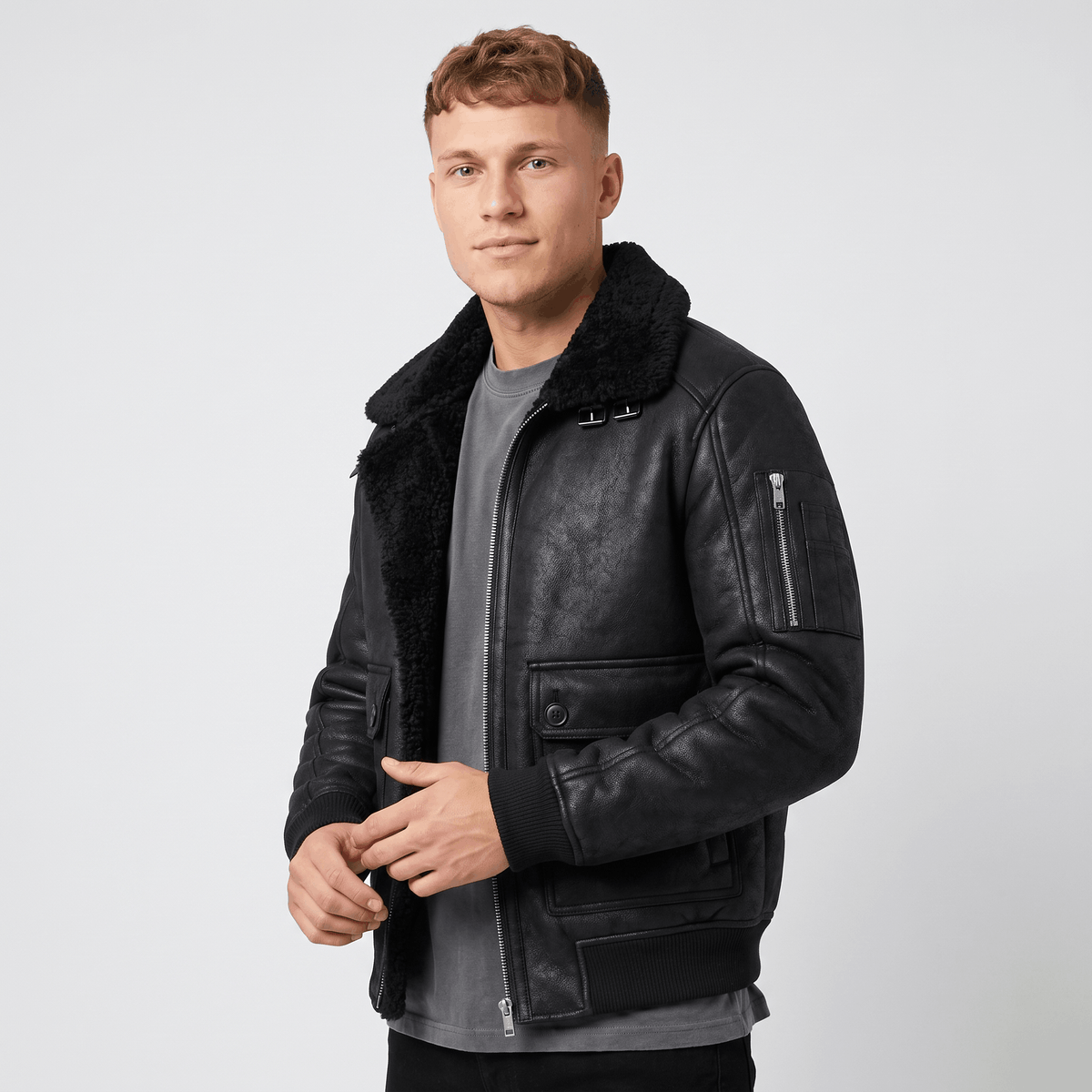A man wearing a black leather shearling jacket with plush lining, a full-zip front, and a shearling collar