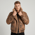 A man wearing a brown leather shearling jacket with plush lining, a full-zip front, and a shearling collar