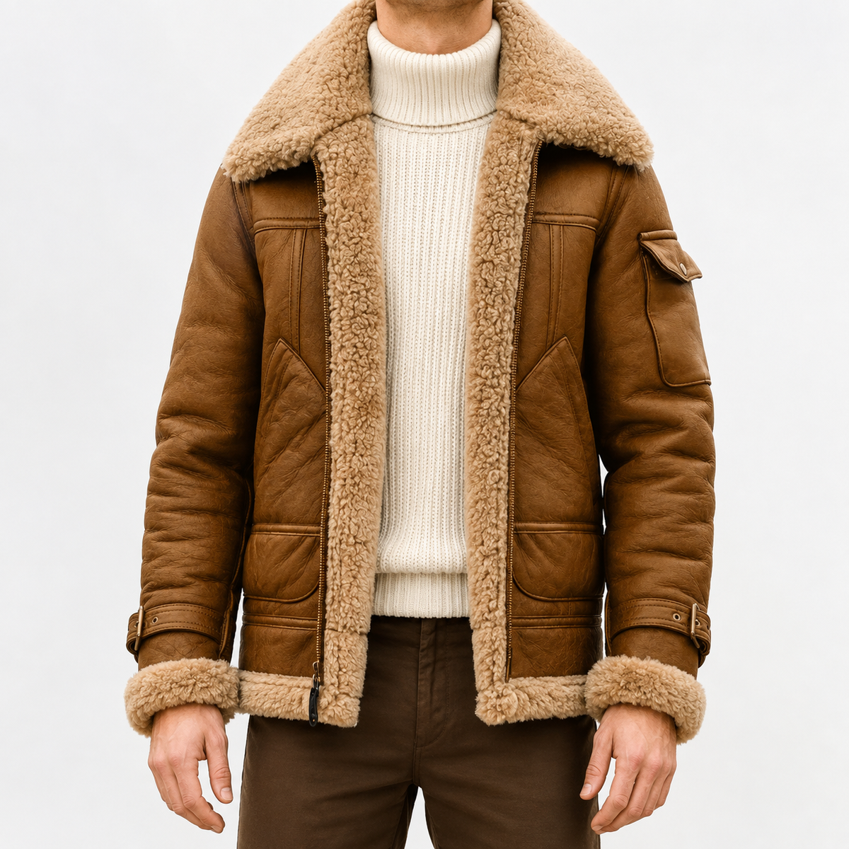 A person wearing a brown leather shearling jacket with sherpa lining, a wide collar, zip front, and biker-inspired style