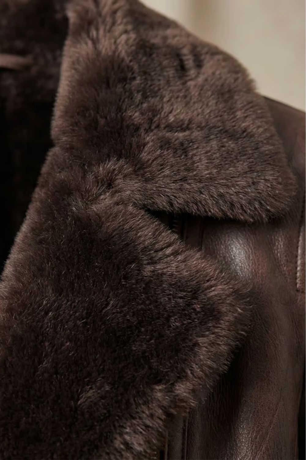 Close-up of a dark brown leather shearling jacket showing the plush shearling lining and textured leather finish
