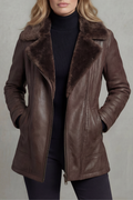 A woman wearing a dark brown leather shearling jacket with a tailored fit, full-zip front, plush shearling collar, and side pockets