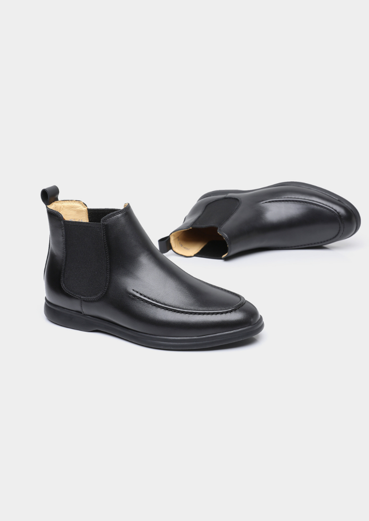Black Chelsea boots with a removable insole displayed beside the boots.
