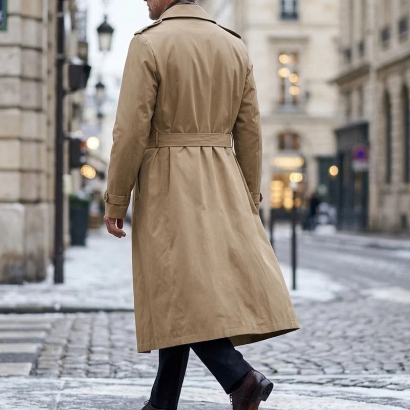 A man wearing a beige long double-breasted trench coat with an adjustable belt and tailored profile, shown from the back