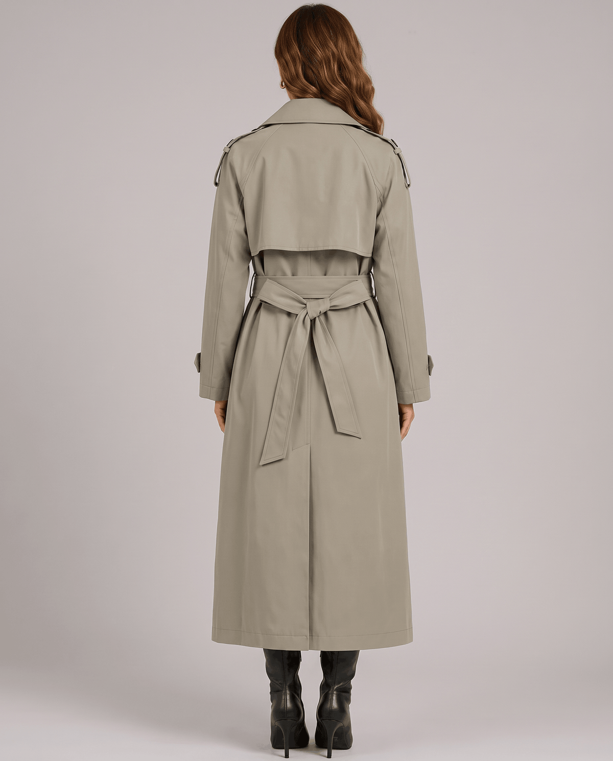 A woman wearing an olive green long trench coat with a double-breasted front and belted waist, shown from the back
