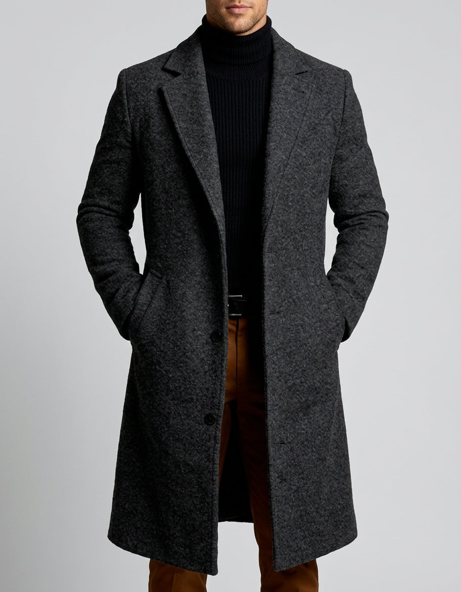 A man wearing a charcoal gray long wool overcoat with a notch lapel and single-breasted fit, shown from the side