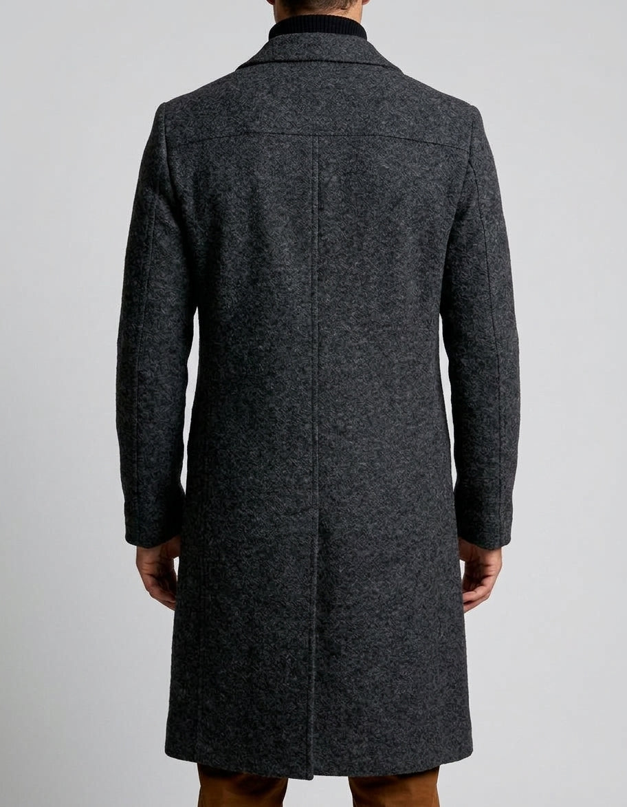 A man wearing a charcoal gray long wool overcoat with a notch lapel and single-breasted fit, shown from the back