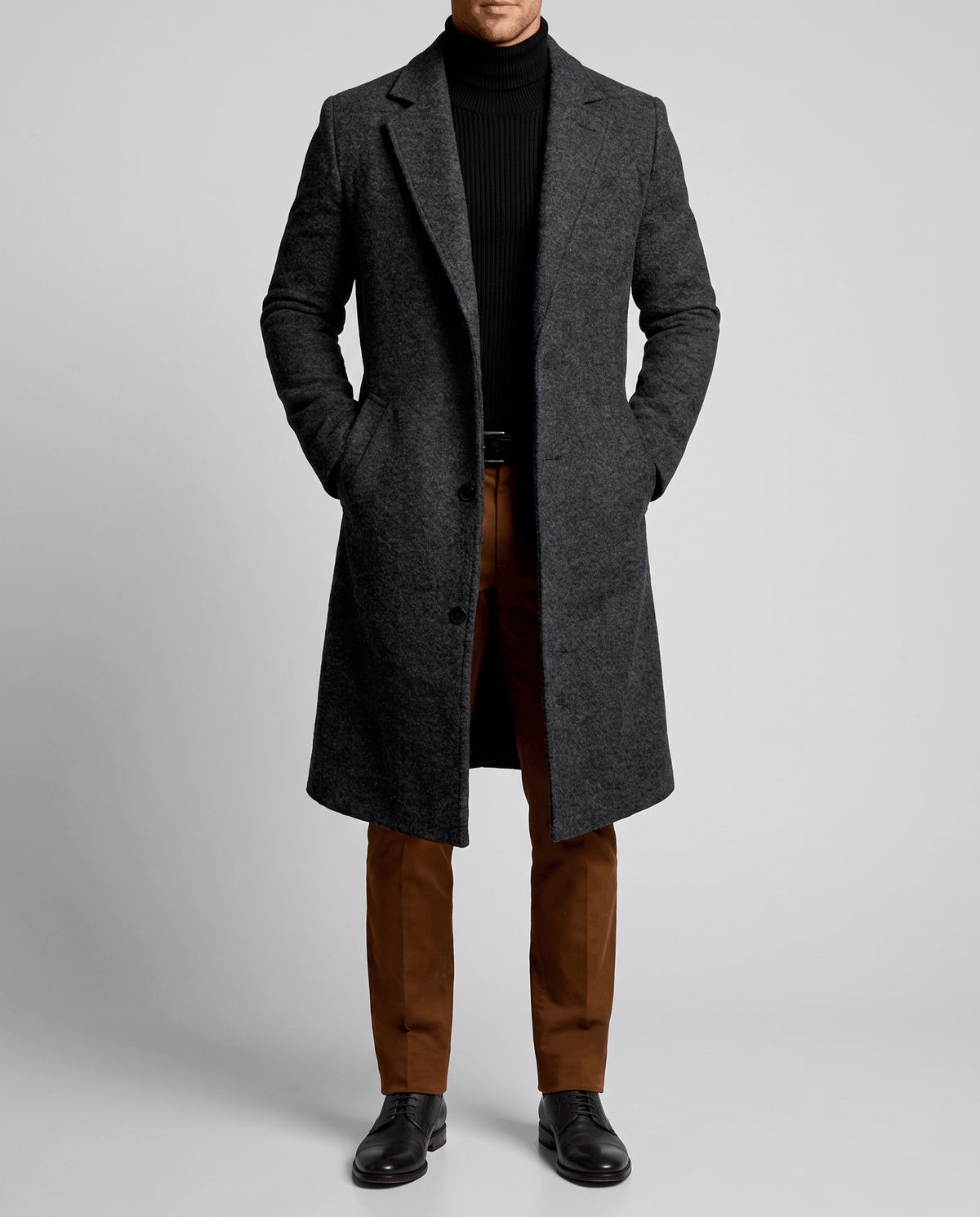 A man wearing a charcoal gray long wool overcoat with a notch lapel and single-breasted fit