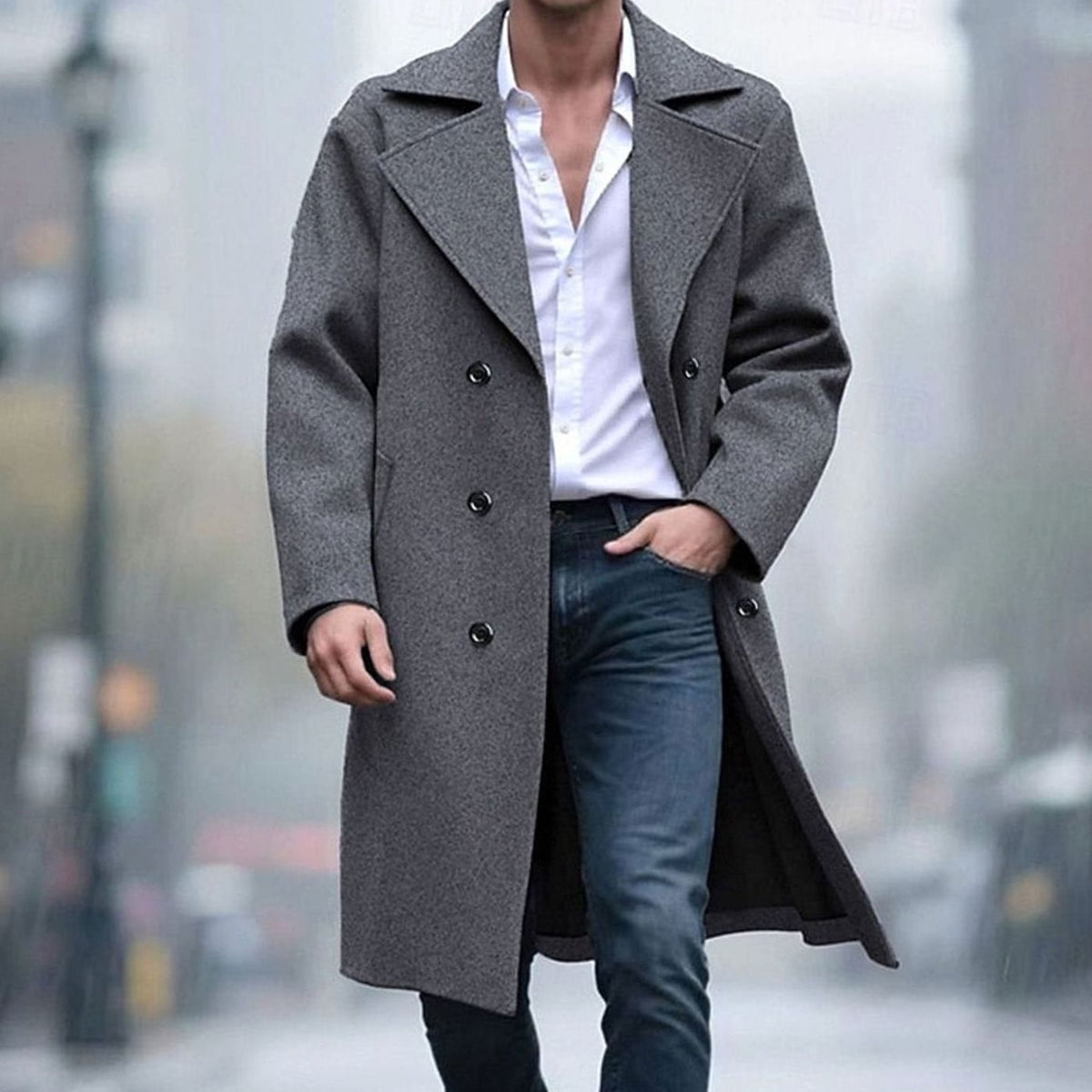 A man wearing a gray long wool trench coat with a double-breasted front and sharp notch lapel, standing outdoors