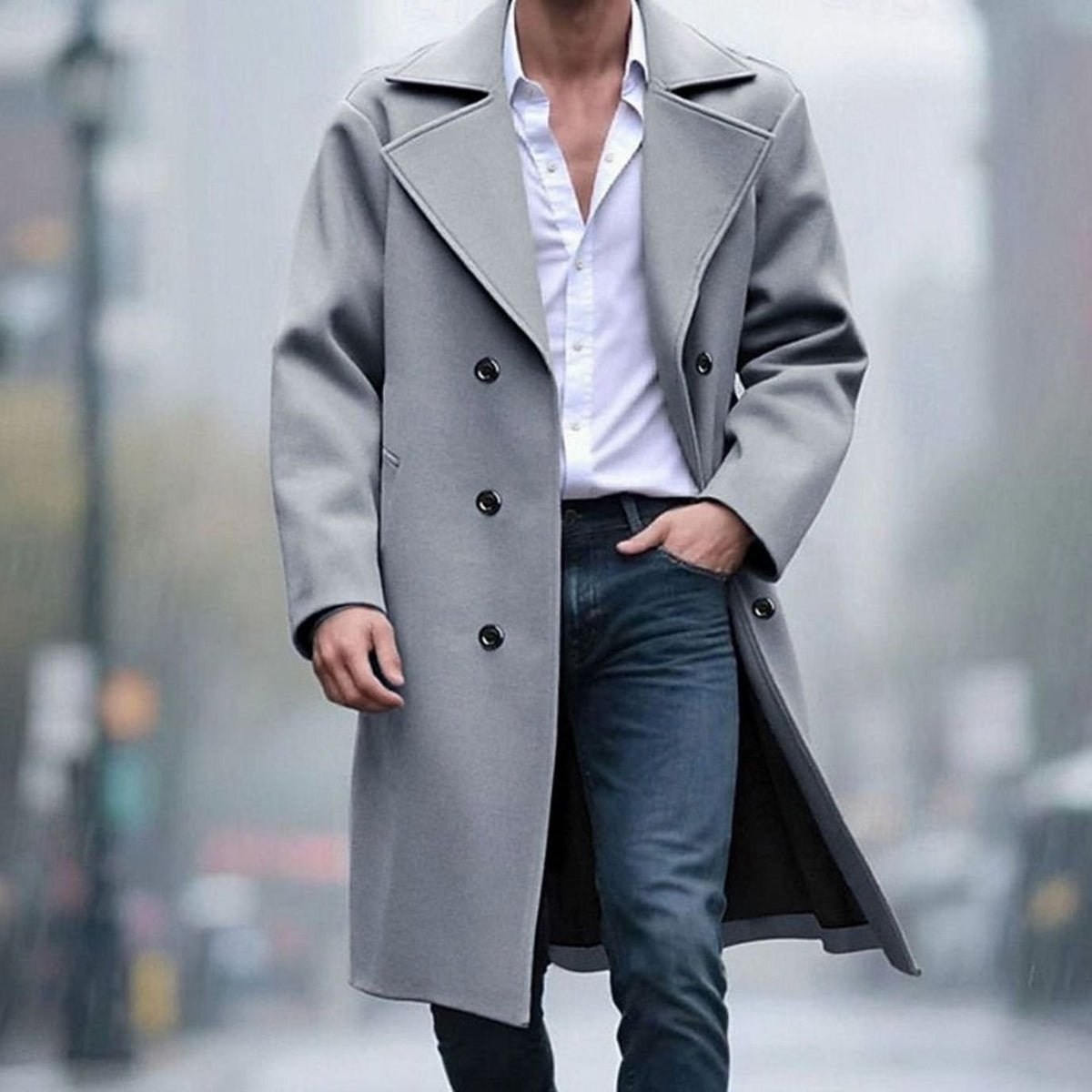 A man wearing a light gray long wool trench coat with a double-breasted front and sharp notch lapel, walking outdoors