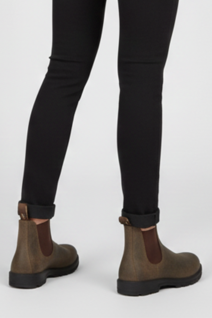 Brown leather Chelsea ankle boots for women with lug sole, worn with black jeans in a three-quarter view