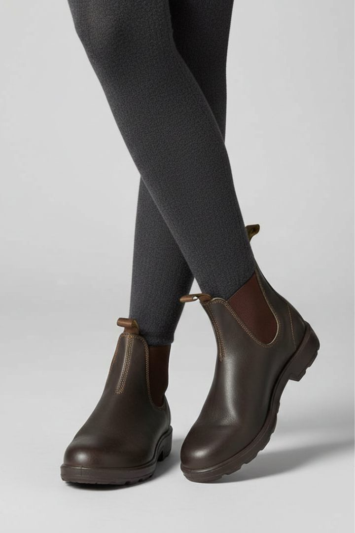 Brown lug sole Chelsea boots for women worn with black skinny jeans, full side view of both boots