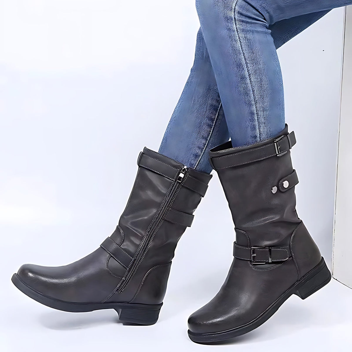 Black knee-high boots with buckle details and low heels worn with jeans.