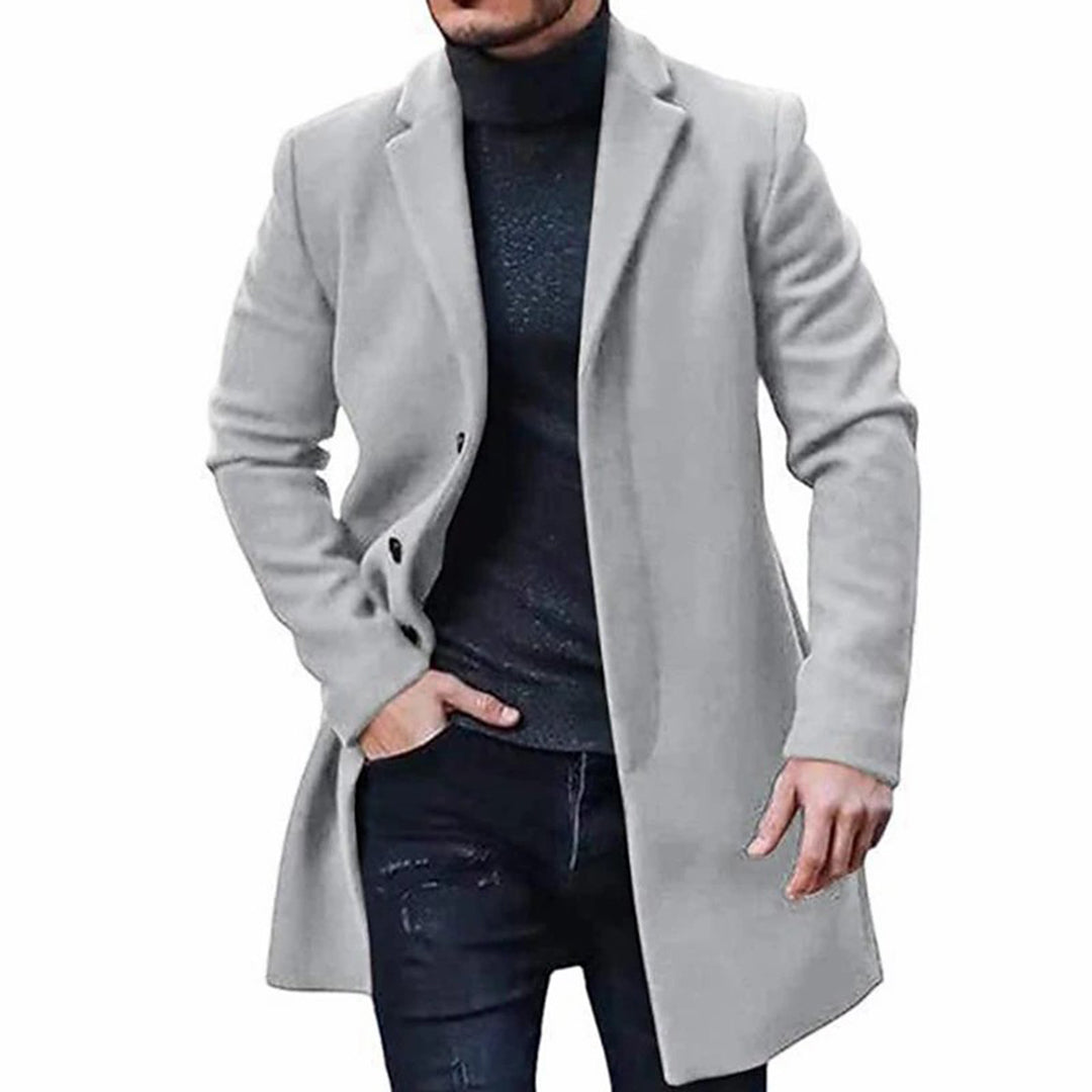 A man wearing a light gray mid-length wool coat with a single-breasted front and tailored fit