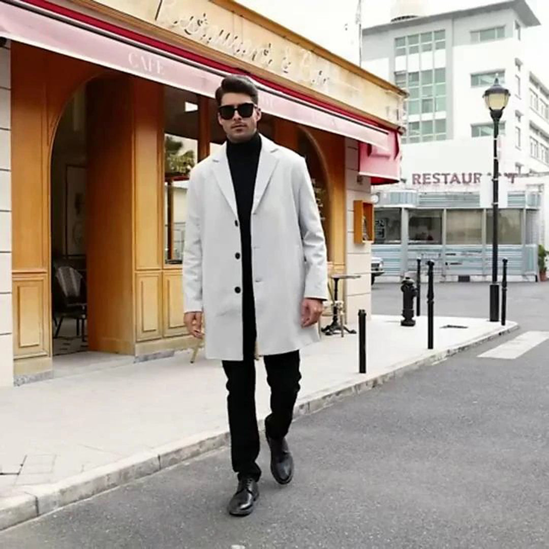 A man wearing a white mid-length wool coat with a single-breasted front and tailored fit, walking on a city street