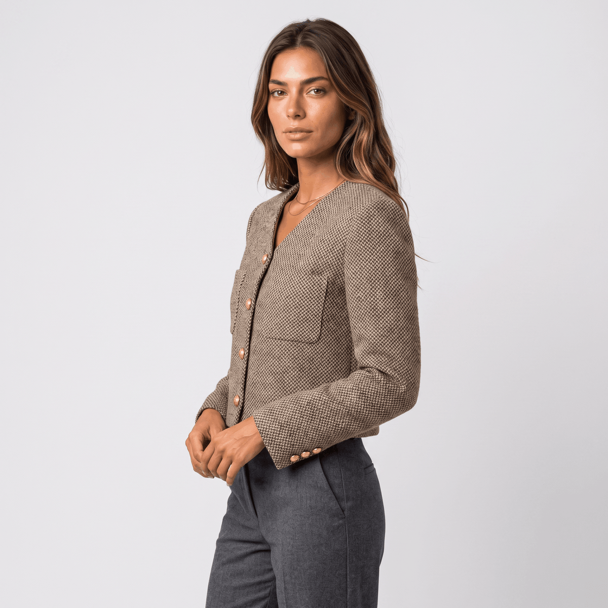 Side view of a woman wearing a brown textured tweed blazer with gold-tone buttons and a fitted silhouette.
