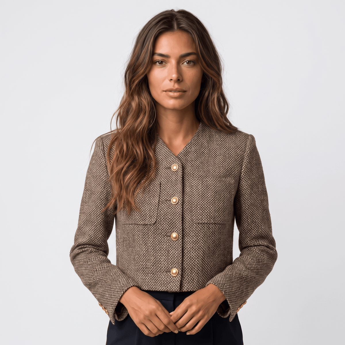 Woman wearing a brown textured tweed blazer with gold-tone button closure, round neckline, long sleeves, and tailored silhouette.