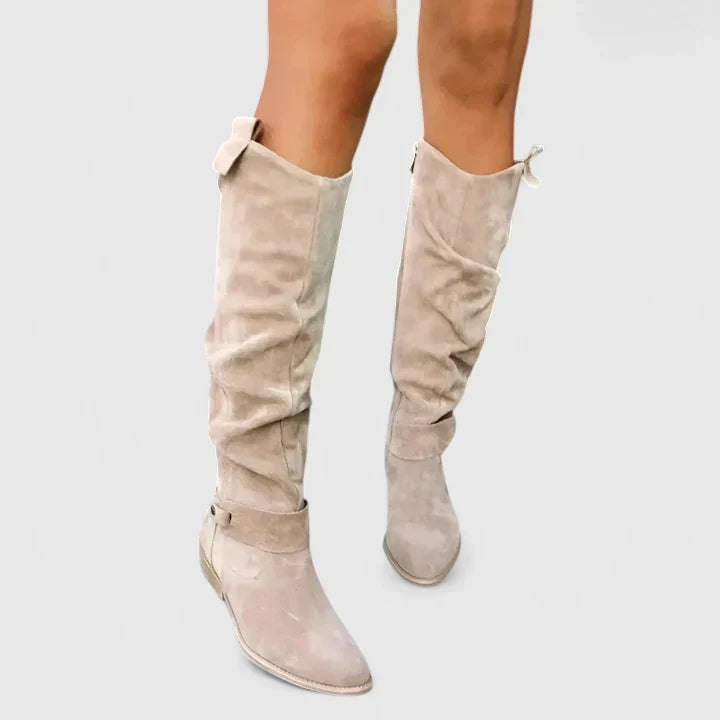 Beige suede over-the-knee boots with a slouchy shaft, almond toe, low block heel, and side snap tab detail.