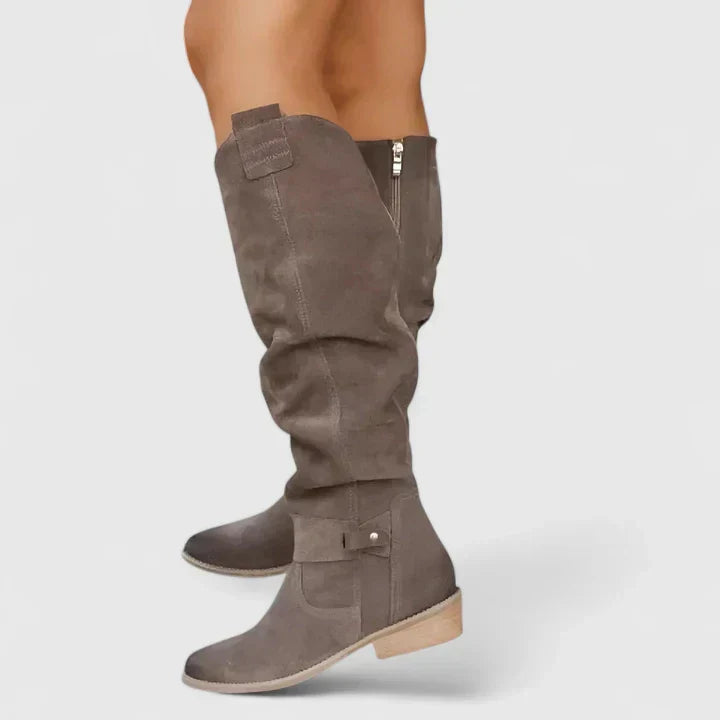 Taupe suede over-the-knee boots with a slouchy shaft, side zip, snap tab detail, and a low block heel.