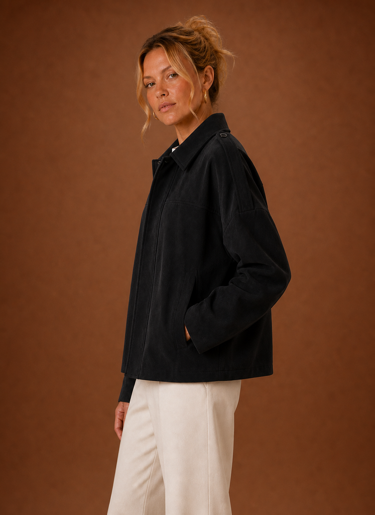 A woman wearing a black oversized suede jacket with a boxy fit and long sleeves, side view