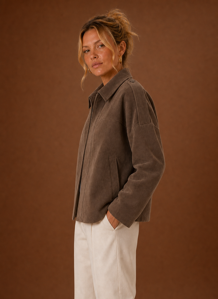 A woman wearing a brown oversized suede jacket with a boxy fit and long sleeves, side view