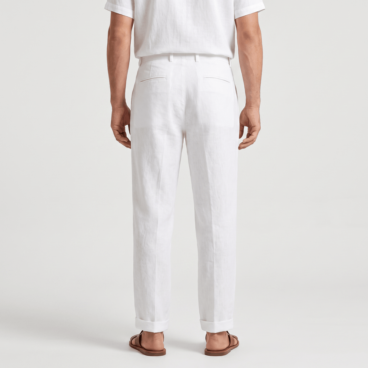 Back view of men's white linen pants with belt loops, a tailored fit, and lightweight linen construction.