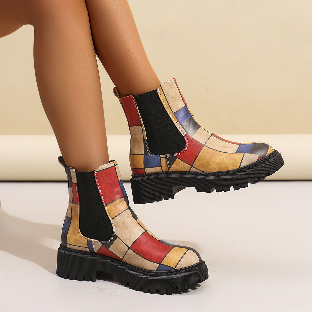 Red, blue and tan geometric panel Chelsea boots for women worn with bare legs, showing the platform height