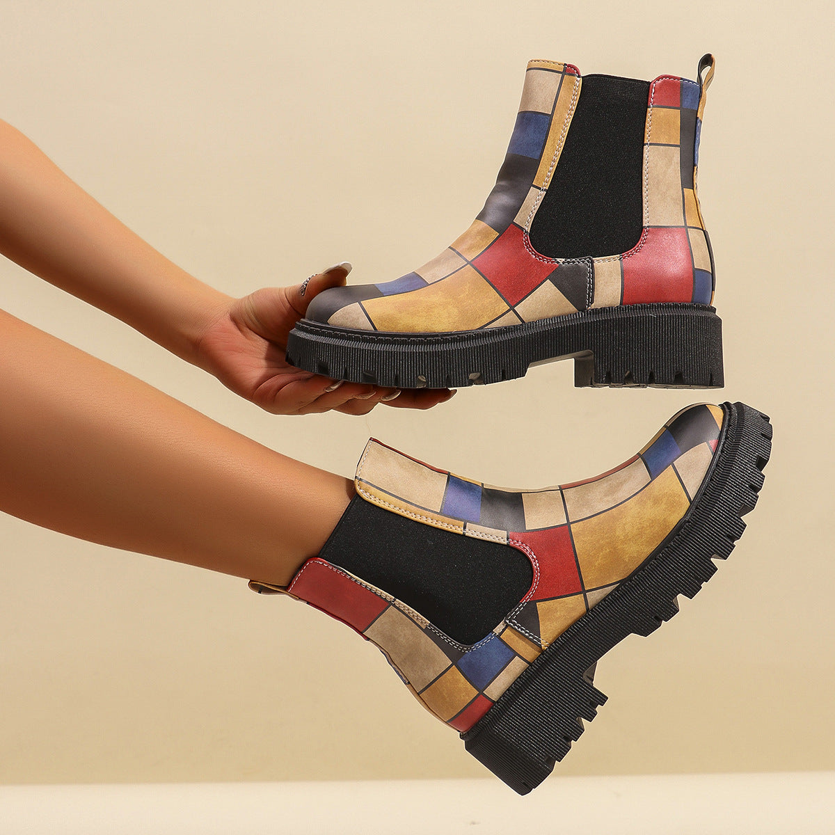 Woman holding a red geometric panel platform Chelsea boot, showing the stitched panels and heel pull tab
