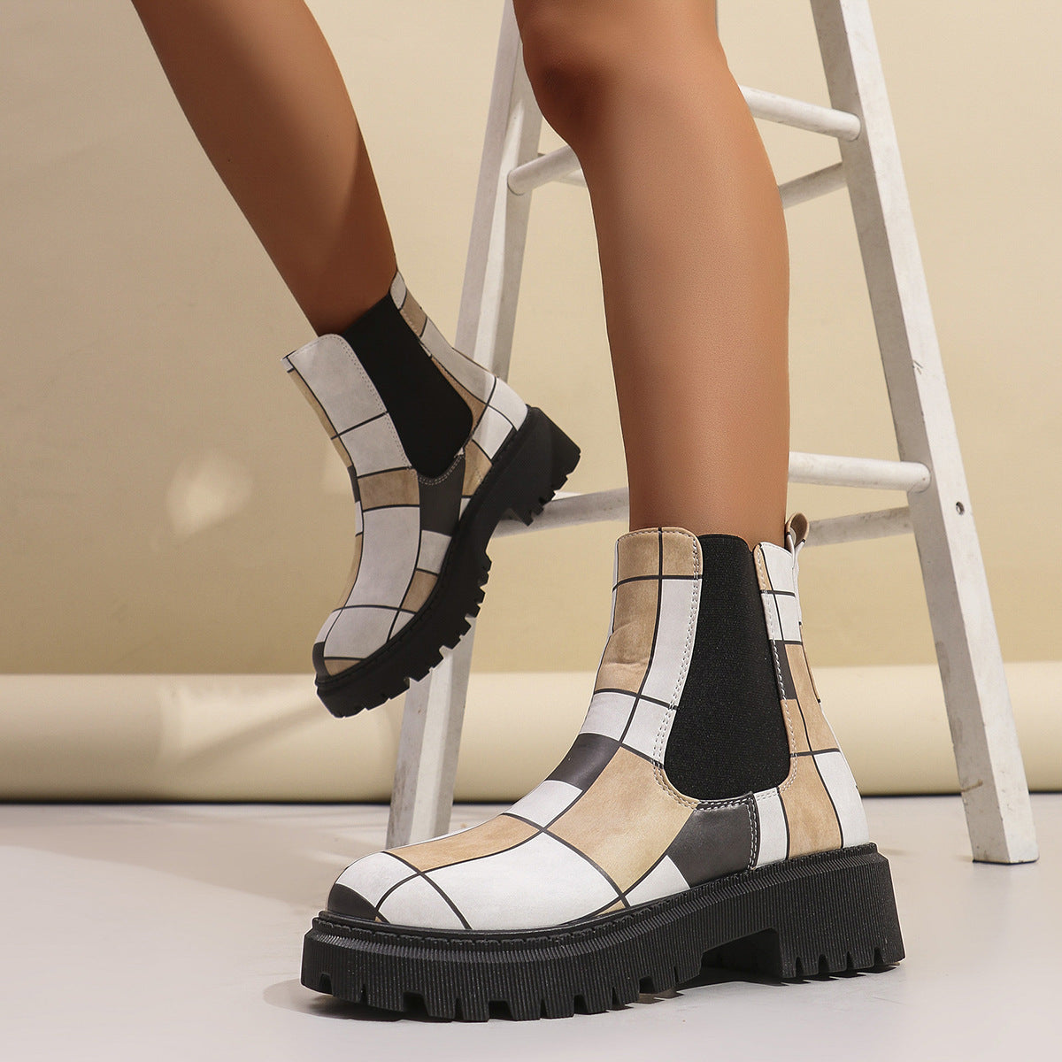 White geometric panel platform Chelsea boots for women worn beside a step ladder, showing the platform height