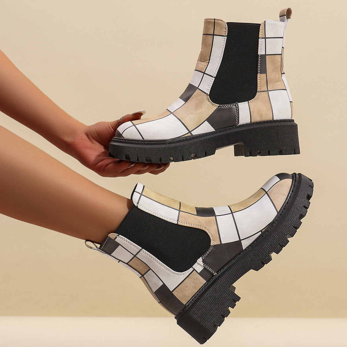 Woman holding a white geometric panel platform Chelsea boot, showing the stitched grid panels and lug sole