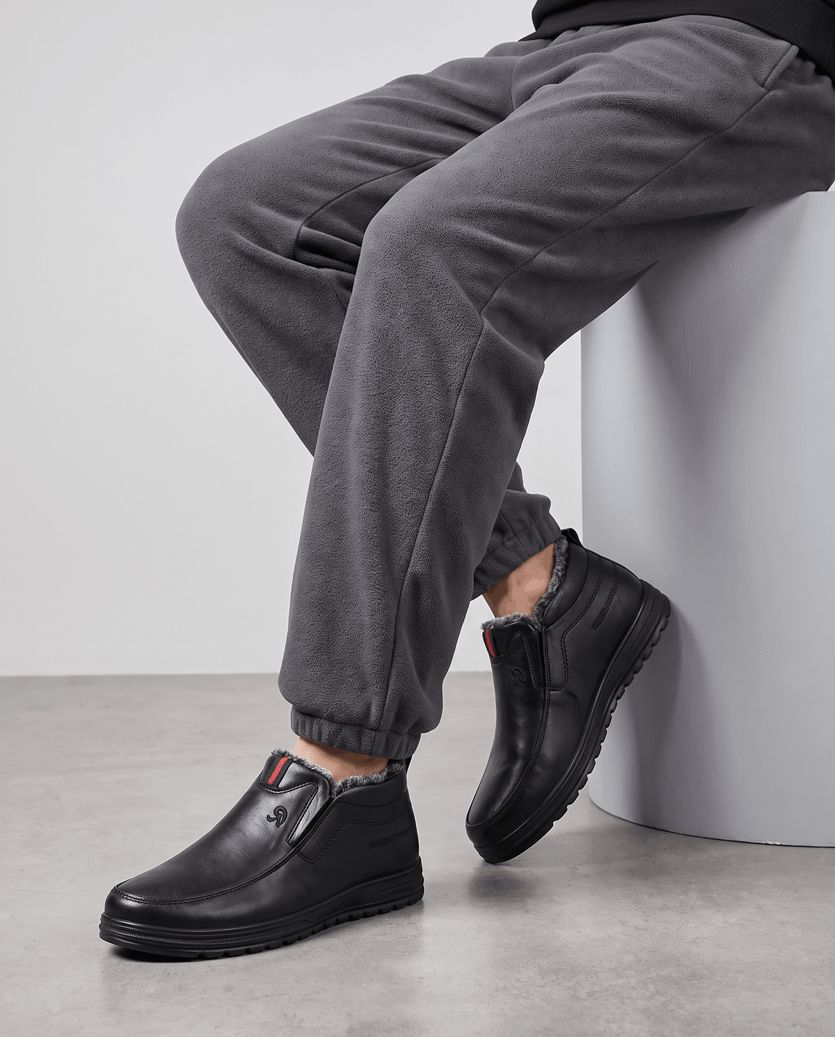 Black plush-lined slip-on winter boots worn with dark trousers