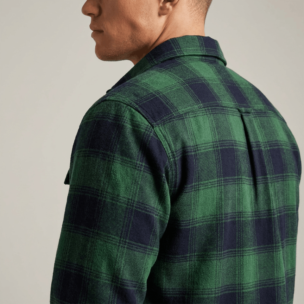 Back view of a man wearing a green and black plaid overshirt jacket with a relaxed fit and long sleeves.