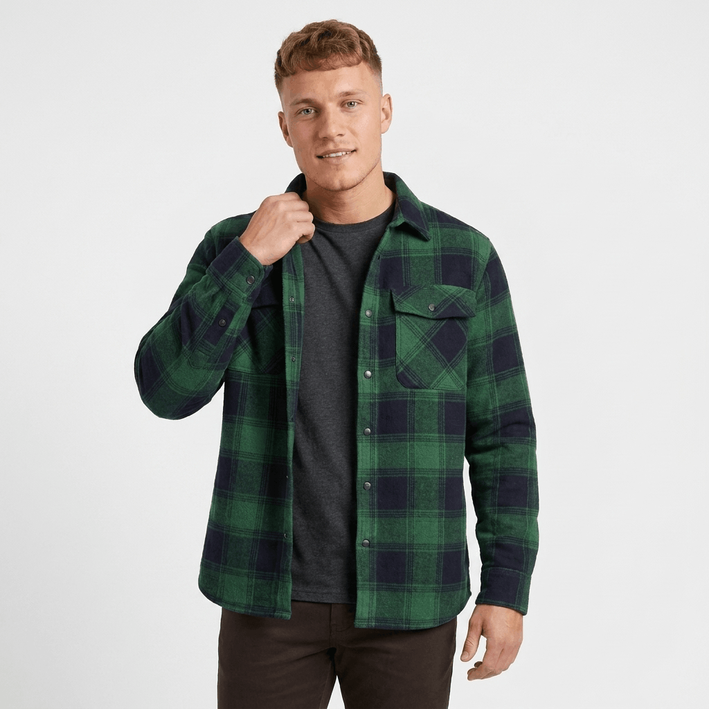 Man wearing a green and black plaid overshirt jacket with a button-front closure, chest pockets, and dark trousers.