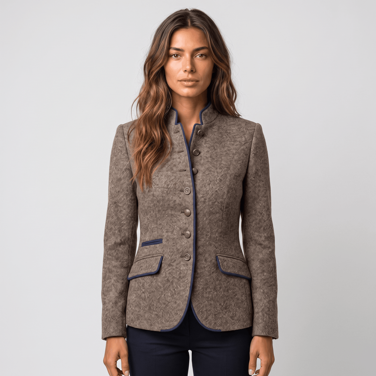 Front view of a woman wearing a brown tweed blazer with navy trim, button closure, flap pockets, and fitted silhouette.