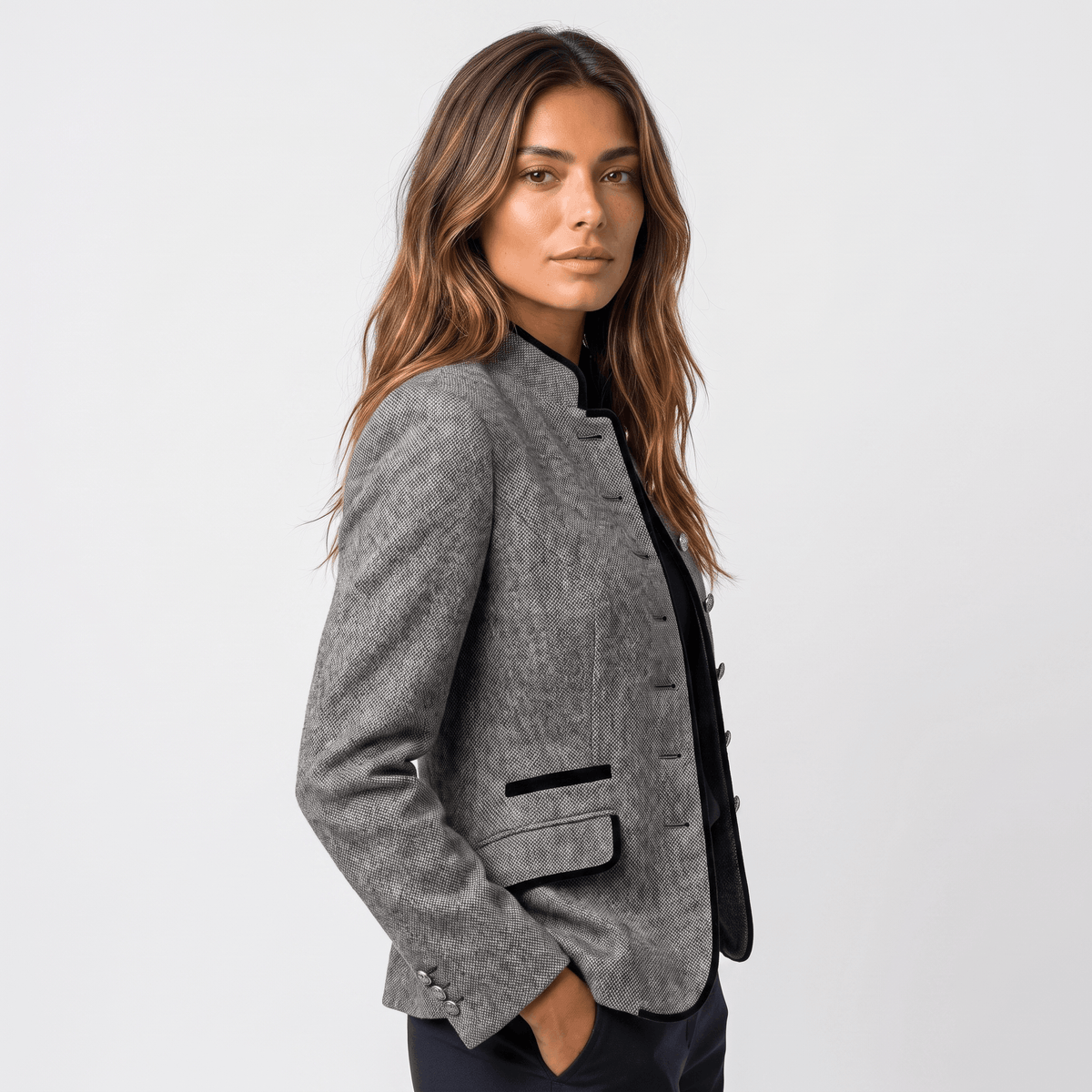 Side view of a woman wearing a gray tweed blazer with dark contrasting trim and a tailored silhouette.