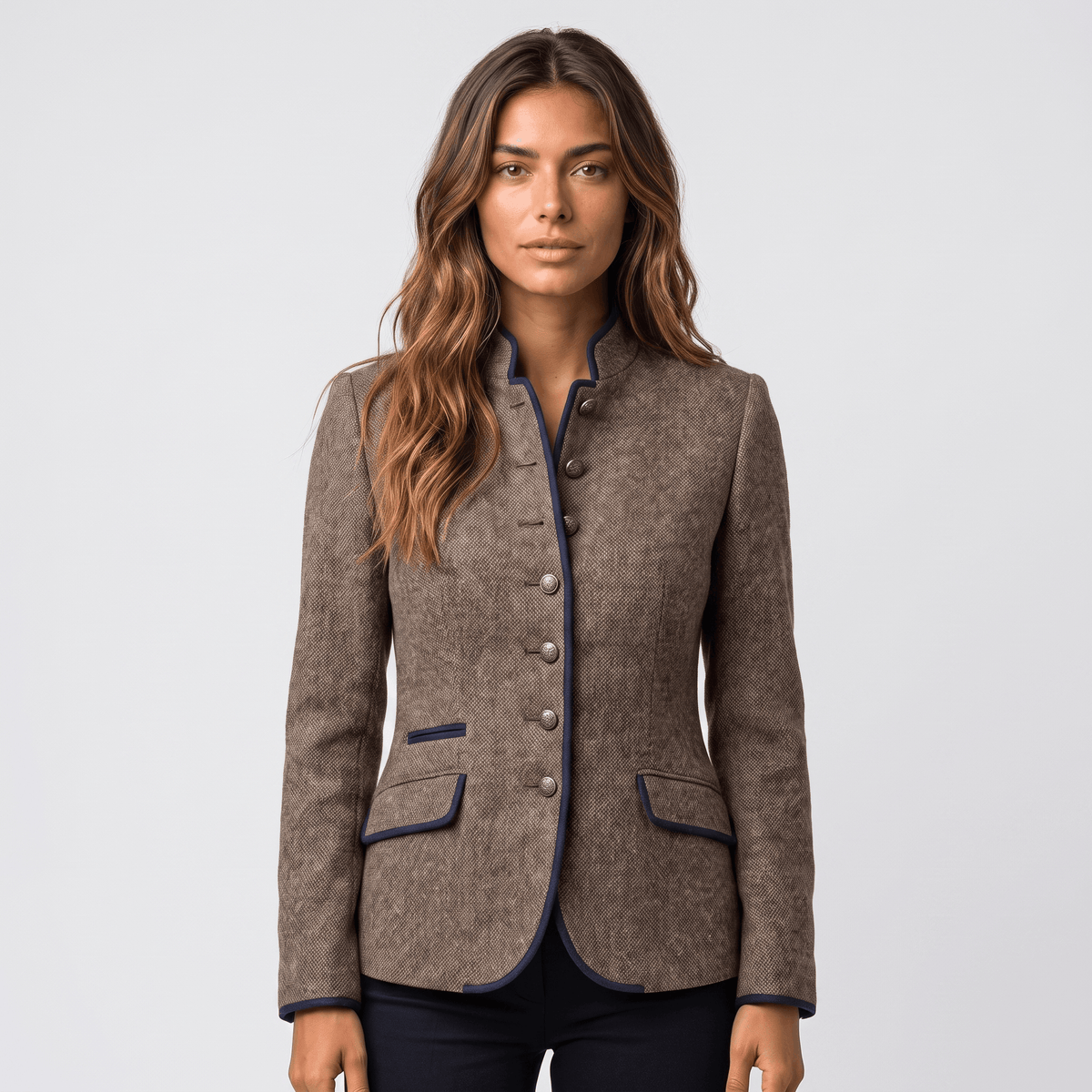 Woman wearing a brown tweed blazer with contrasting navy trim, button-front closure, notched collar, and flap pockets.