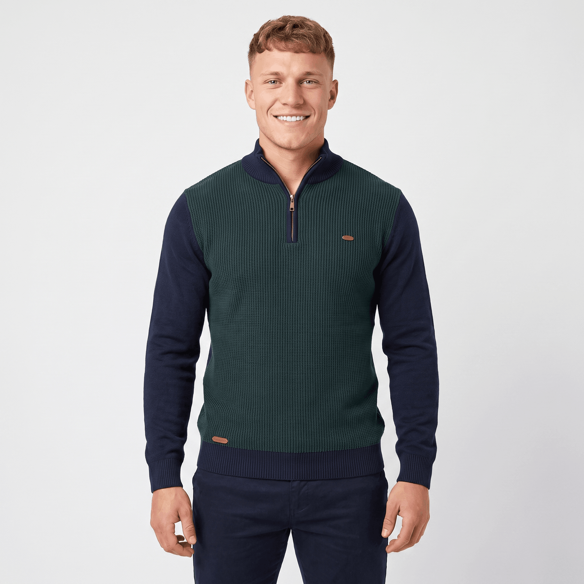 Man wearing a green color block quarter-zip knit sweater with navy sleeves, ribbed texture, stand collar, and long sleeves.