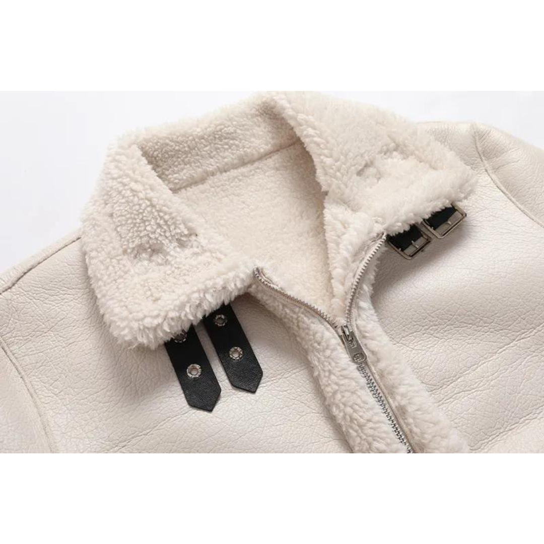 Close-up of a white shearling leather jacket showing the plush-lined buckle collar and front closure