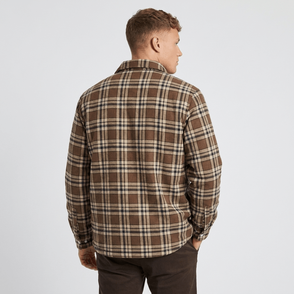 Back view of a man wearing a brown and cream plaid sherpa-lined overshirt jacket with a relaxed fit and long sleeves.
